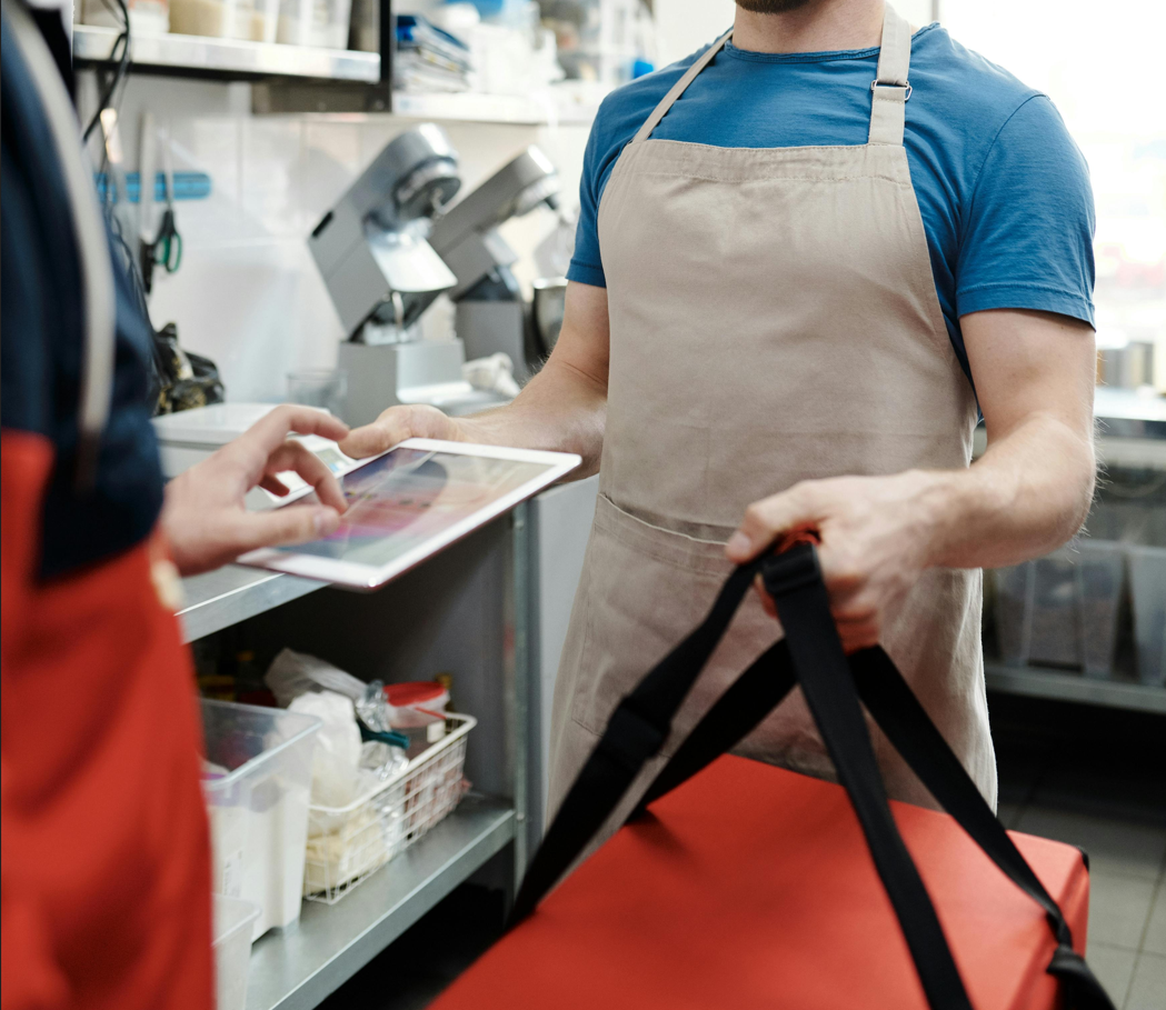 Ghost kitchen workspace showing packaged food and an online ordering system on a tablet.